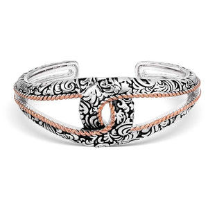 A silver-tone cuff bracelet with intricate engravings and rose gold rope detailing, featuring an openwork interlocking design.